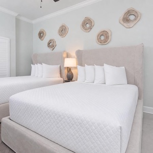 Drift off on plush queen beds beneath a warm lamp and fluff pillows for a restful retreat in this guest room