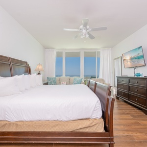 Spacious master bedroom featuring a king bed, additional twin and sleeping chair, flat-screen TV, and stunning balcony views