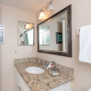 Guest bathroom featuring a granite countertop, stylish mirrors, and colorful accents for a refreshing retreat