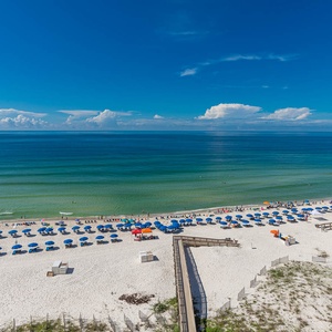 Enjoy the view of a serene beach lined with colorful umbrellas under a clear blue sky, perfect for a relaxing getaway