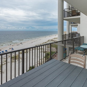 Enjoy stunning beachfront views from this balcony, featuring a dining table and comfortable seating for relaxation