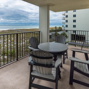 Balcony seating with a round table overlooks the beach and tranquil gulf waters, creating a perfect spot for relaxation