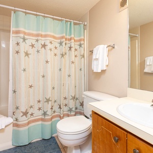 This bathroom features a starfish-patterned shower curtain, fresh towels, and a clean, inviting space for relaxation