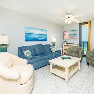 Bright living area features a blue sofa with queen sleeper, patterned chairs, and a dining table