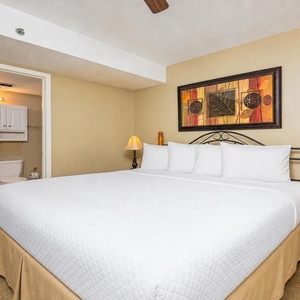 King bed with plush linens, warm tones, and a charming artwork above, creating a relaxing atmosphere
