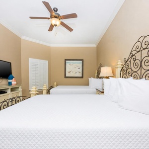 This guest bedroom features two comfortable full beds, a flat-screen TV, and soft beige walls, creating a relaxing atmosphere