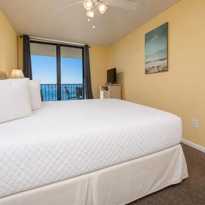 Cozy master bedroom featuring a king bed, a flat-screen TV, and a breathtaking view from the balcony