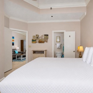 Relax in the spacious bedroom featuring a king bed, decorative art, and a view into the inviting living area