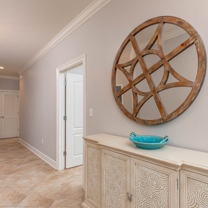 This hallway features elegant decor, including a decorative mirror and a stylish cabinet, enhancing your arrival experience