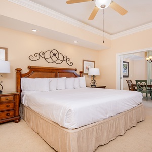 Elegant master bedroom featuring a plush king bed and a cozy seating area with a view of the dining space