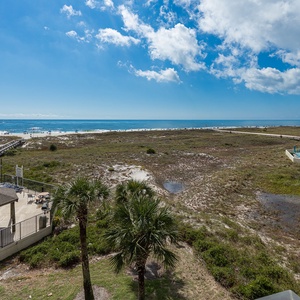 Gulf views stretch across the beach, framed by swaying palm trees and a relaxing pool area with lounge seating