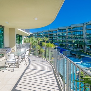 Enjoy views of the vibrant pool, lazy river, and waterslide from your balcony, surrounded by lush greenery