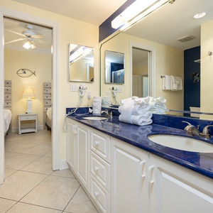 Bright guest bathroom featuring dual sinks, plush towels, and a glass-enclosed walk-in shower