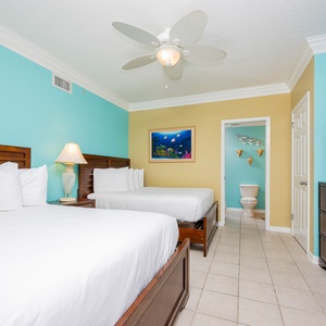 Relax in this colorful guest bedroom featuring two queen beds, a flat-screen TV, and vibrant décor