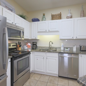 Bright white cabinetry complements the stylish countertops in this kitchen, featuring stainless appliances