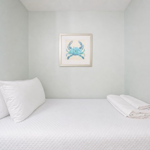 Twin bed featuring white linens and charming nautical decor on soft blue walls