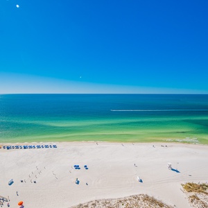 Enjoy breathtaking views of the beach from this bright space with a serene blue sky and inviting sandy shore