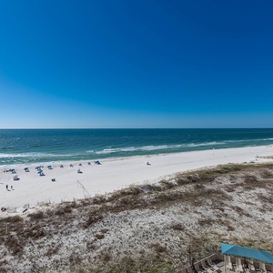 Gaze at the inviting shoreline and enjoy the vibrant beach scene from your comfortable outdoor space