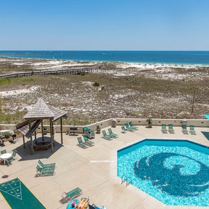 Expansive views of the beach complement the inviting pool area, featuring lounge chairs and a shaded seating space