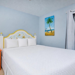 This guest bedroom features a colorful starfish headboard, cozy bedding, and a lovely view through the sliding glass door