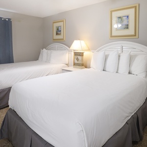 Guest bedroom featuring two double beds, soft bedding, and a bedside lamp, complemented by framed artwork on the walls