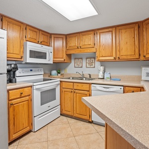 This kitchen features wooden cabinetry, a white stove, and a stainless refrigerator, creating a functional and inviting space