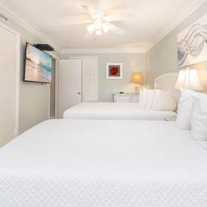 Relaxing guest room featuring two queen beds, a TV, and coastal decor for a relaxing atmosphere