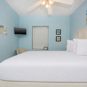 The guest bedroom features a queen bed, while decorative art enhances the inviting atmosphere of this bedroom