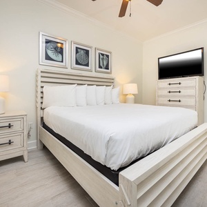 This guest bedroom features a stylish king bed, a wall-mounted TV, and soft lighting, creating a relaxing retreat