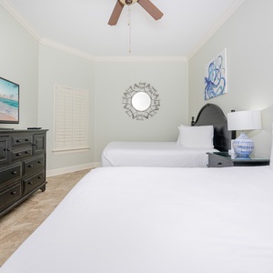 Bright and inviting guest bedroom featuring two queen beds, a flat-screen TV, and coastal-inspired decor