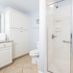 Experience a relaxing shower after a day at the beach in this guest bath with stylish cabinetry and spacious vanity