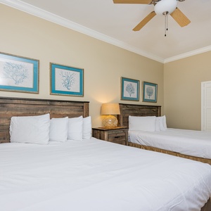 Rest in this cozy guest bedroom featuring two queen beds, charming decor, and soft lighting