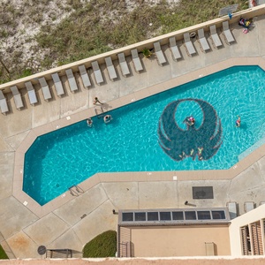 Aerial balcony view of a pool area featuring sun loungers, vibrant pool toys, and guests enjoying the refreshing water