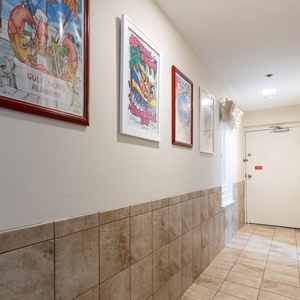 Walk down a charming hallway adorned with colorful artwork, leading to your inviting vacation retreat