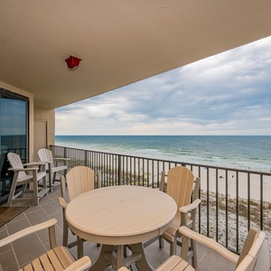 Relax at the patio table with chairs, enjoying the view of the water and beach from your spacious balcony