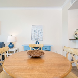 The dining area features a round wooden table, blue accents, and a cozy couch, perfect for relaxing and enjoying meals
