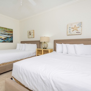 Cheerful guest bedroom featuring two cozy queen beds and charming nautical artwork for a relaxing retreat
