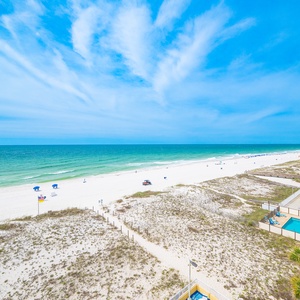 This stunning beachfront view showcases soft white sands and vibrant blue waters, perfect for a relaxing getaway