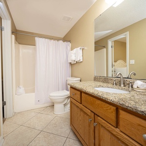 Experience the guest bathroom with a spacious granite countertop and a relaxing tub-shower area