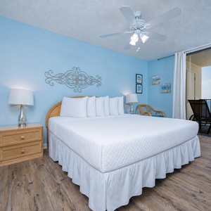 Spacious master bedroom featuring a king bed, coastal decor, and a balcony with serene water views