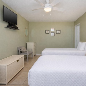 This guest bedroom features two beds, a mounted TV, and charming decor, creating a relaxing retreat for visitors