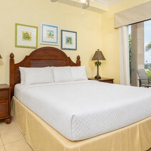Relax in the master bedroom with a comfortable king bed, tropical decor, and access to the outdoor patio