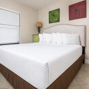 Experience comfort in this inviting guest bedroom with a plush king bed, decorative art, and warm lighting for a restful stay