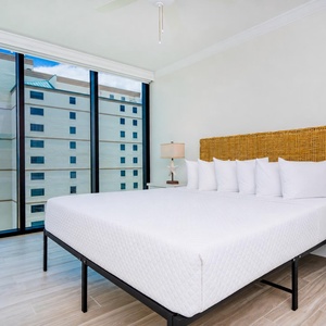 Spacious guest bedroom featuring a king bed, stylish decor, and expansive windows with views of the coast