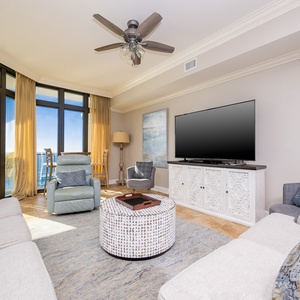 This living area features a cozy seating arrangement, a large TV, and stunning beachfront views through expansive windows