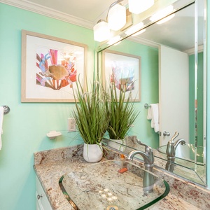 Bright and inviting guest bathroom featuring a stylish granite countertop, modern fixtures, and vibrant aqua walls