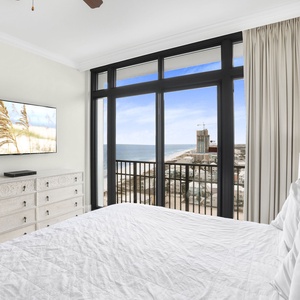 The master bedroom features a king bed, large TV, and offers stunning views of the beachfront from the balcony door
