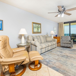 Cozy living area features a striped sofa with queen sleeper, accent chairs, and a view of the balcony