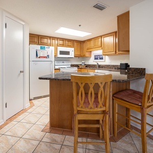 Wooden cabinetry complements the granite countertops in this inviting kitchen area with a breakfast bar and seating