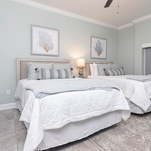 Unwind on soft, fluffy queen beds and read by the warm bedside lamp beneath framed coral art in this guest room